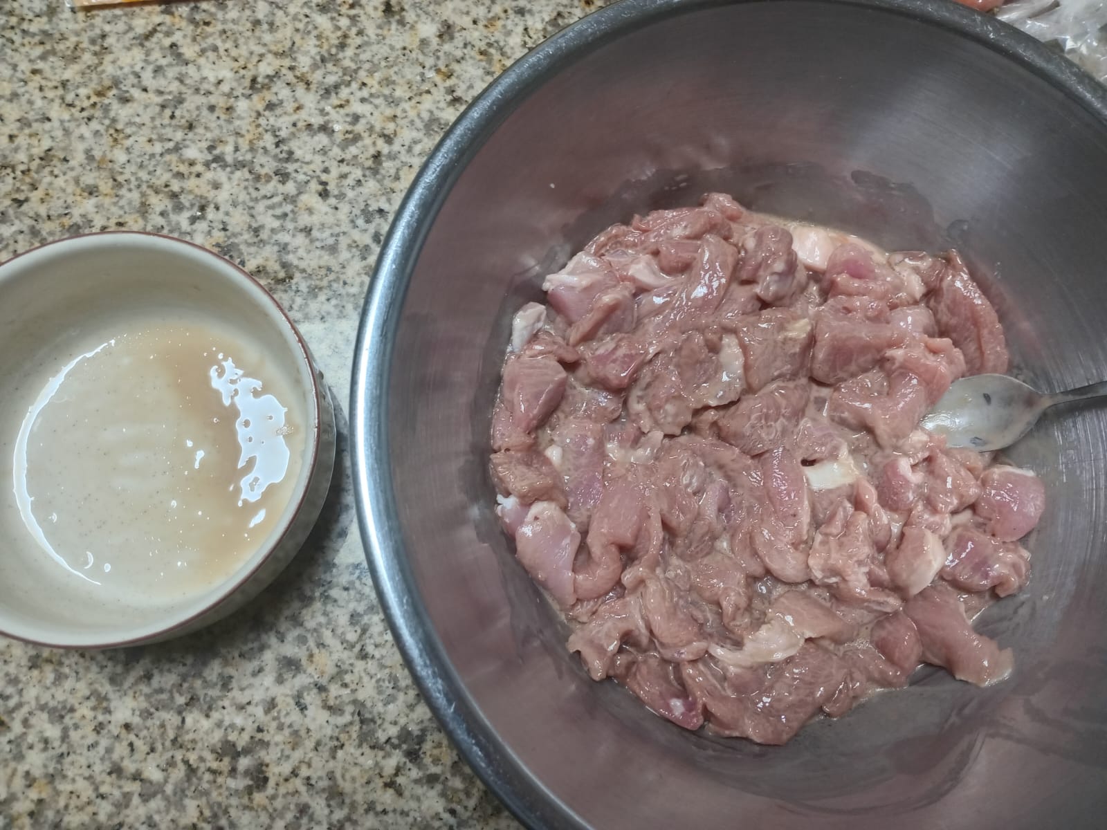 bite-size pork pieces in a steel bowl with the marinade poured over