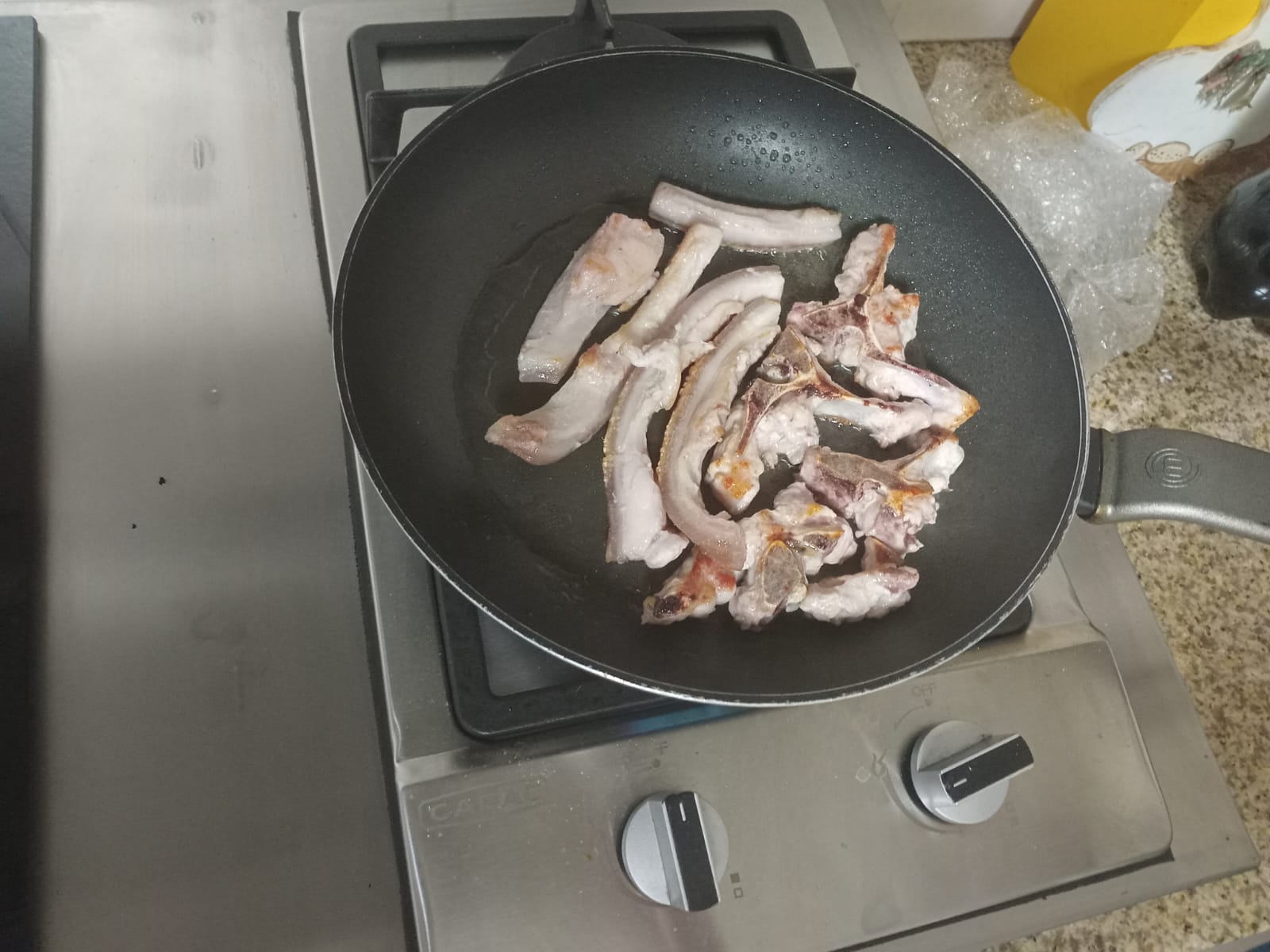 pork bones and crackling frying in a pan on their own