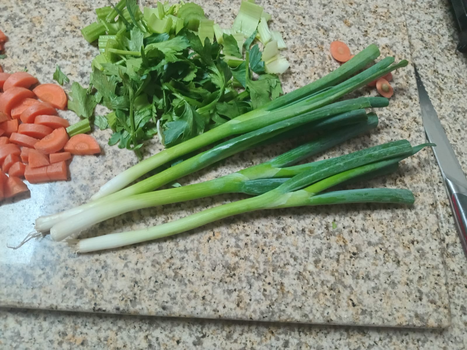 whole spring onions beside the chopped carrot and celery